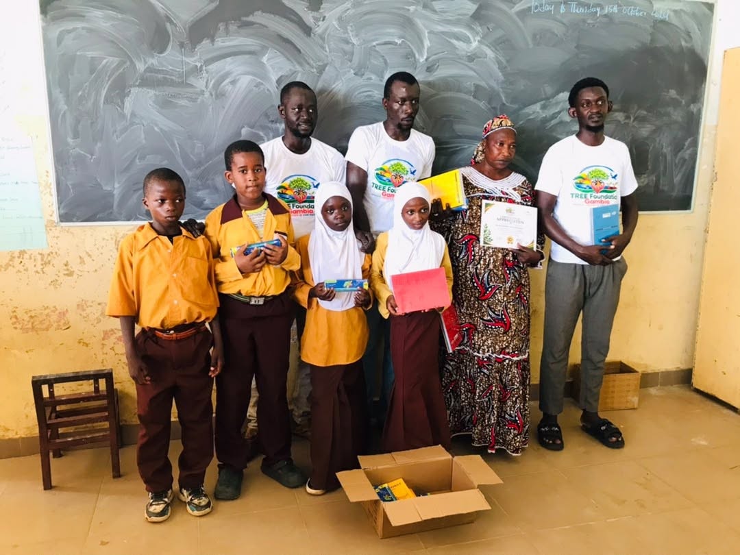 TREE Foundation Gambia team presenting learning materials and certificates to pupils